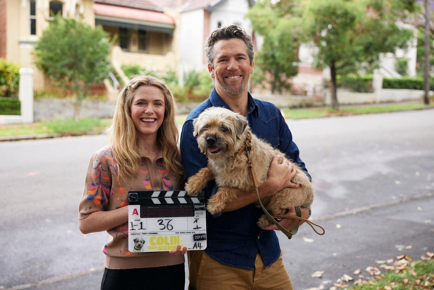 Two members of the Easy Tiger team on a Colin from Accounts set, holding a clapperboard and their dog