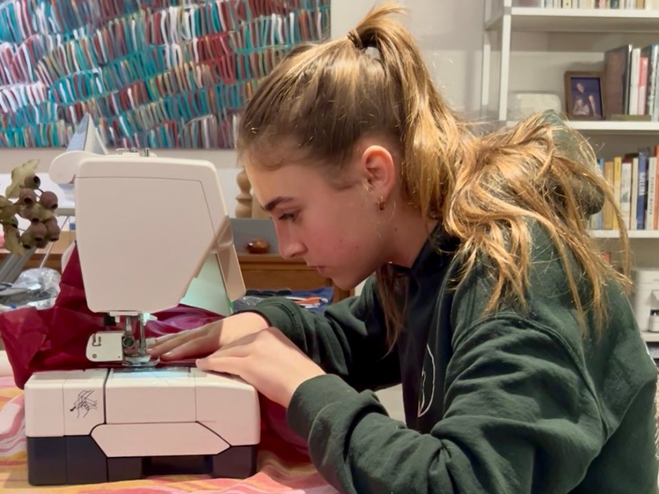 Stella at a sewing machine working on costumes for a local theatre production