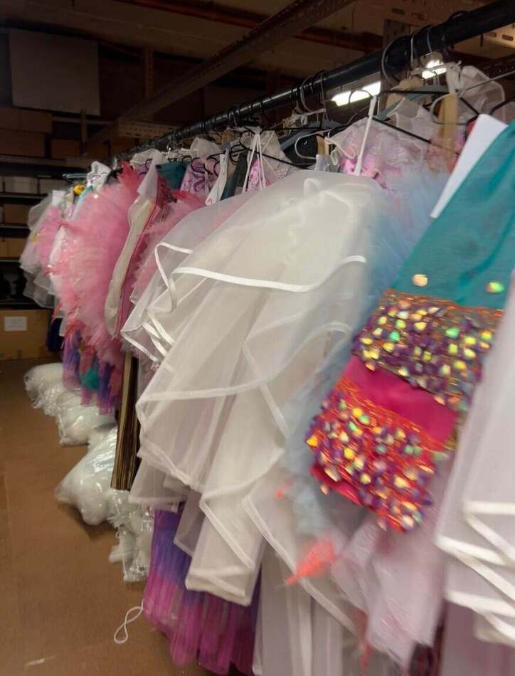 A rack of colourful opera costumes with a white tutu in front, backstage at Opera Australia