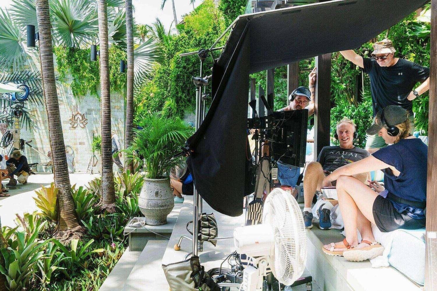 Mike White watching a monitor on set, under a shade tent, wearing headphones